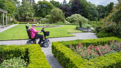 A visitor using a motorised scooter enjoys the Walled Garden at Penrhyn Castle